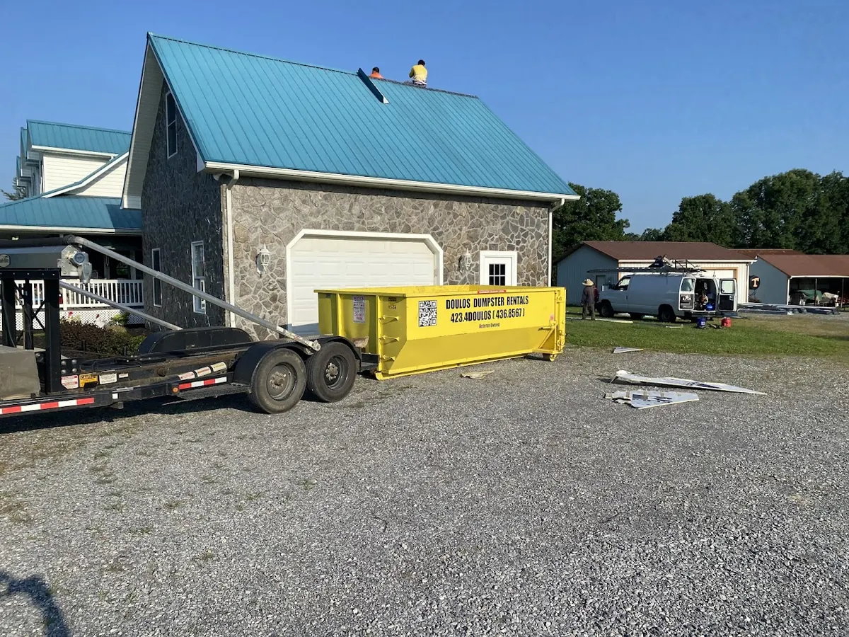 Dumpster beside a house during a roofing tear off
