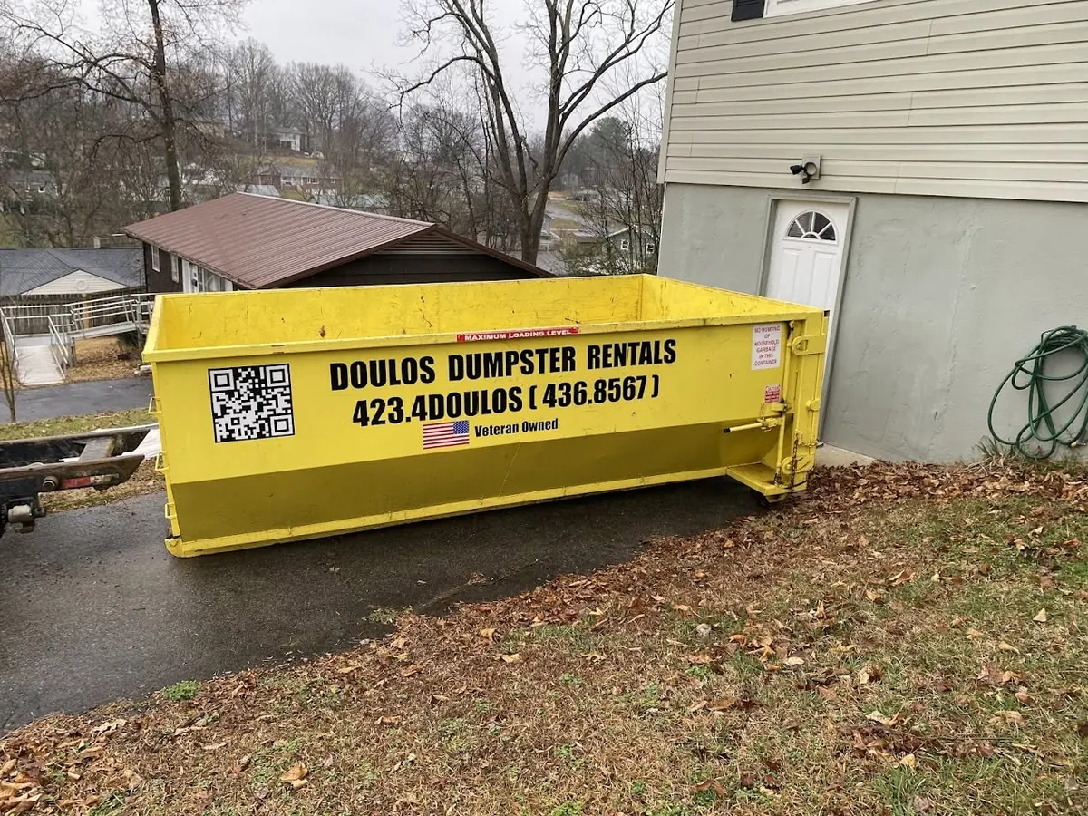 Dumpster placed on a sloped driveway at a hillside home
